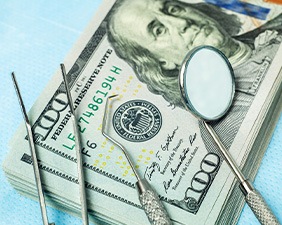 Dental instruments on a pile of $100 bills