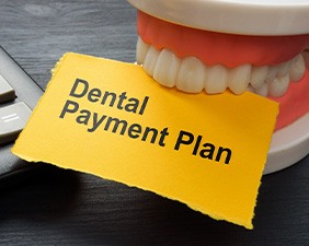 Fake teeth biting yellow paper that says “Dental Payment Plan”