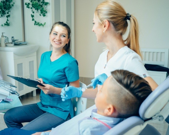 Caring dental team members laughing with dental patient