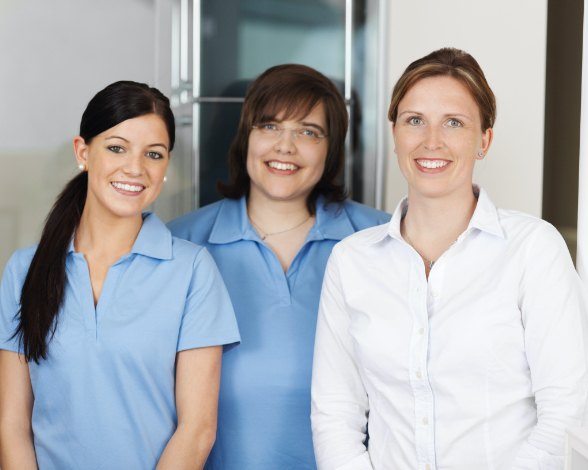 Three smiling dental team members