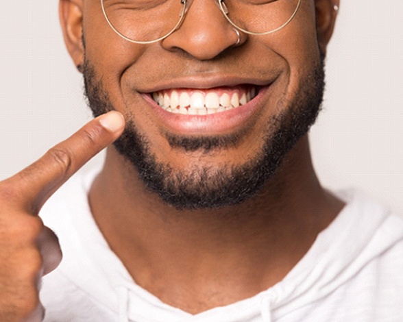 Closeup of man pointing to his All-On-4 dental implants in Pacoima