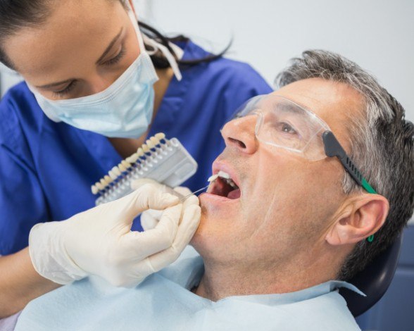 Man's smile compared to porcelain veneers shade during cosmetic dentistry visit