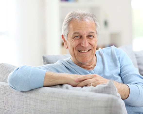 Senior man with dentures in Pacoima, CA sitting on couch