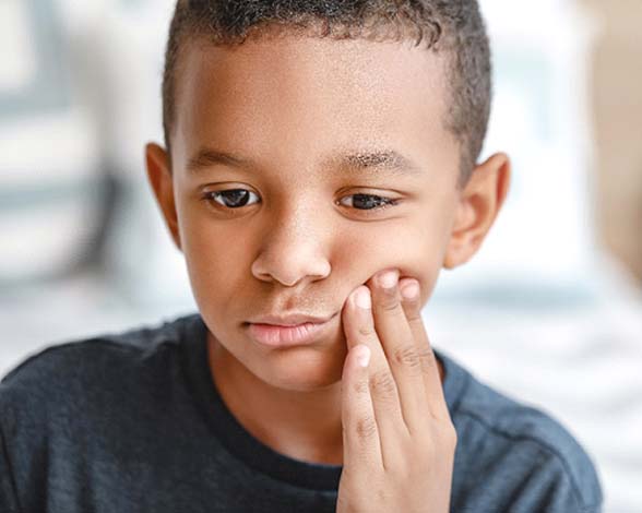 Child with a dental emergency in Pacoima holding his cheek