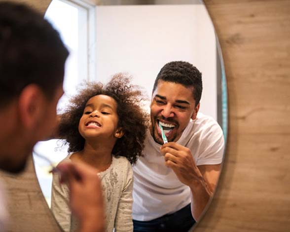 Father and daughter preventing dental emergencies in Pacoima by brushing