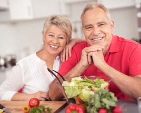 Older couple smiling after preparing a healthy meal