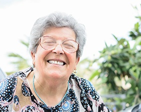 Woman with dental implants smiling outdoors