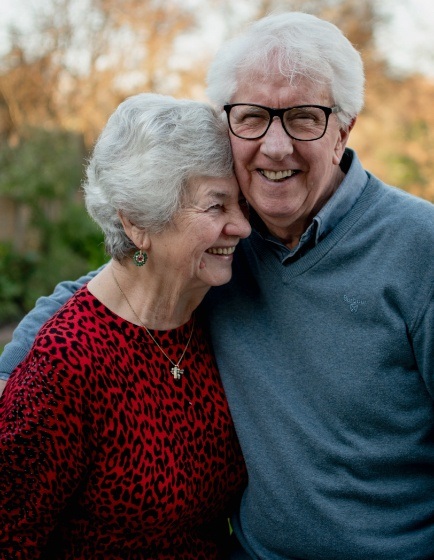 Senior man and woman smiling and hugging outdoors