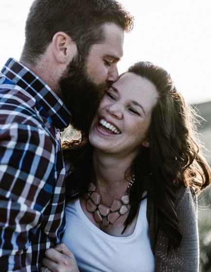 Man kissing laughing woman outdoors