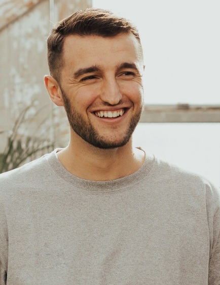 Man with gray sweater smiling outdoors