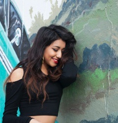 Young woman standing beside artwork on wall