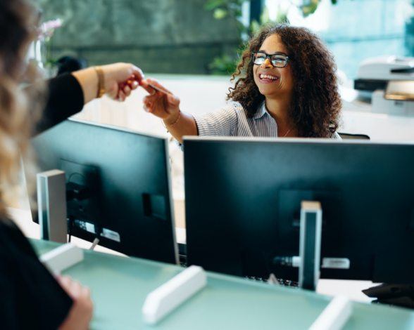 Woman handing dental team member her dental insurance card