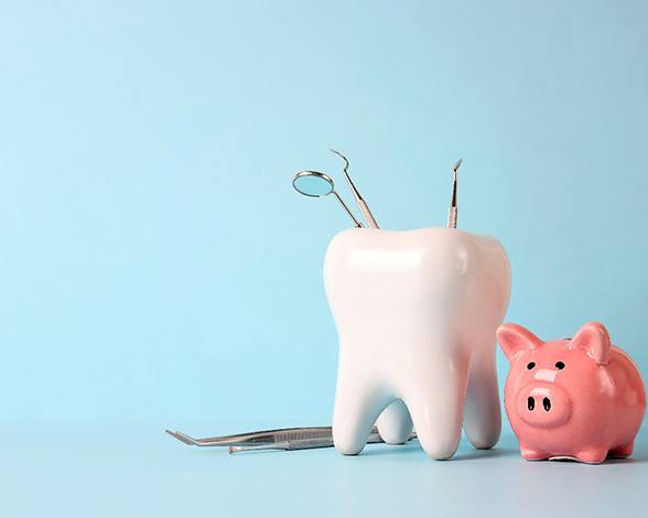 A model tooth sitting next to a piggy bank 