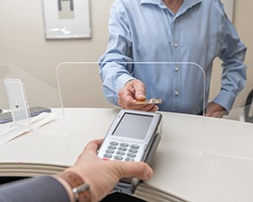 A man paying the cost of Invisalign