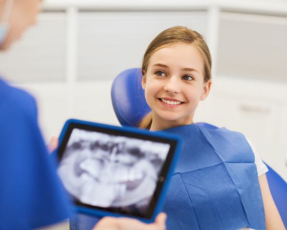 Dentist reviewing young girl's x-rays during children's dentistry visit