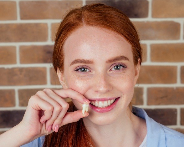 Woman holding up wisdom tooth after extraction