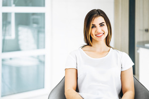 Woman in white shirt smiling in dental chair